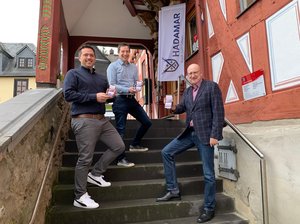 Jonas Partsch, Jens Kremer (beide webfacemedia) und Bürgermeister Michael Ruoff präsentieren die Hadamar-App auf ihren Smartphones..