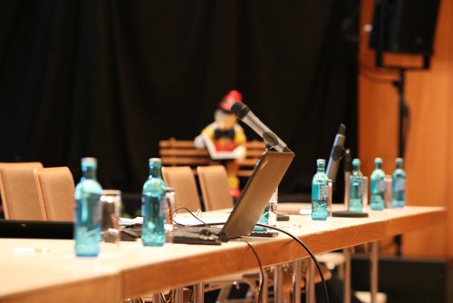 Auf einem Symbolbild einer politischen Versammlung in der Stadthalle Hadamar sieht man die Mikrofone und einen Laptop der Sitzungsleitung.